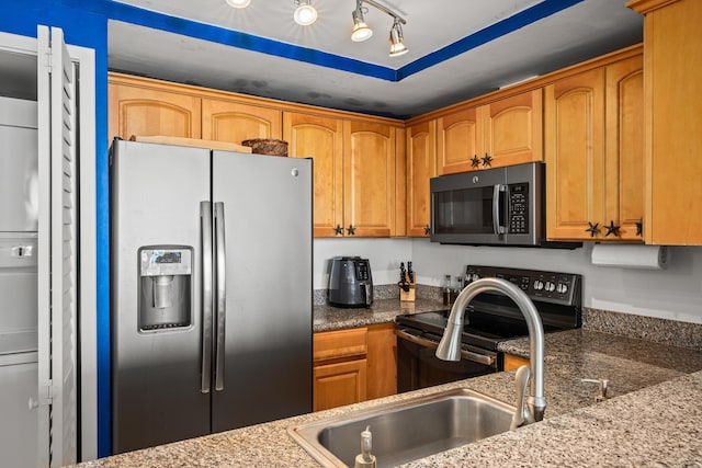 kitchen featuring sink, stainless steel appliances, dark stone countertops, and track lighting