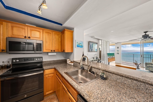 kitchen with black electric range oven, ceiling fan, sink, a water view, and track lighting