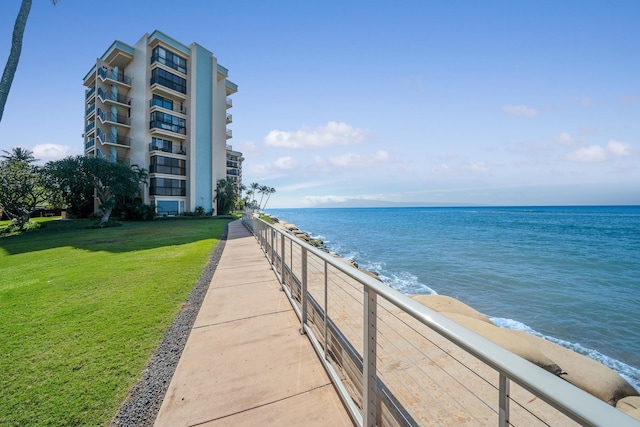 view of home's community with a water view, a beach view, and a yard