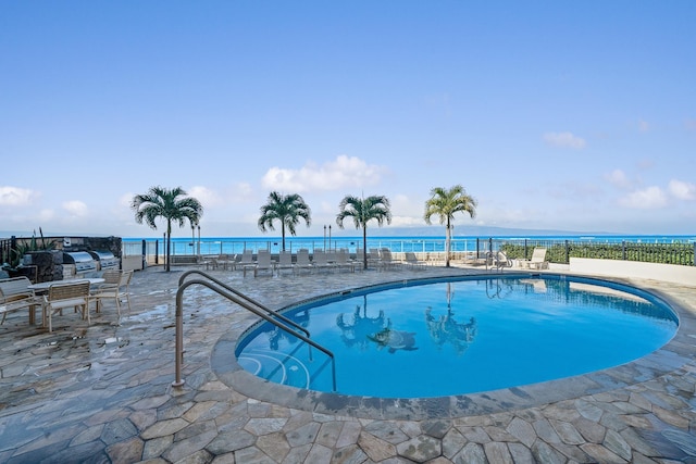 view of swimming pool with a patio and a water view