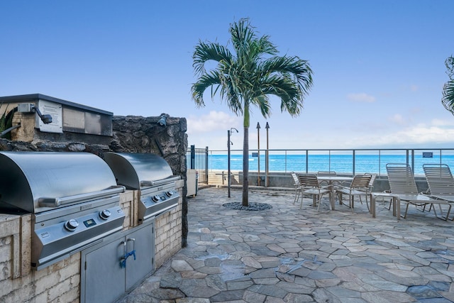 view of patio / terrace with a grill, a water view, a view of the beach, and area for grilling