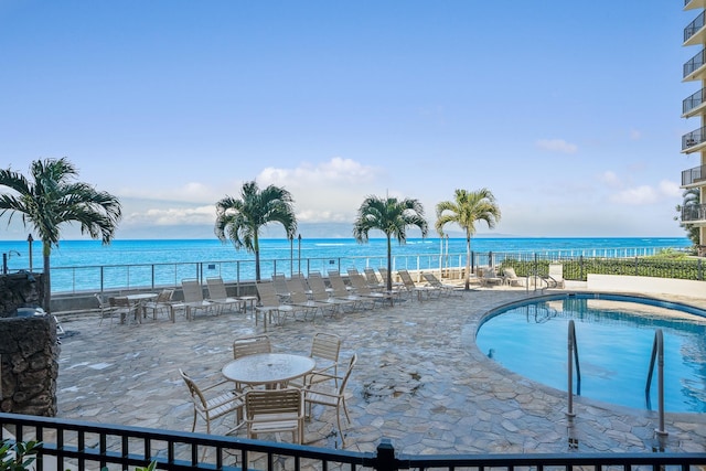 view of swimming pool featuring a patio and a water view