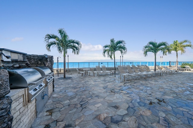 exterior space with a grill, a water view, a beach view, and area for grilling