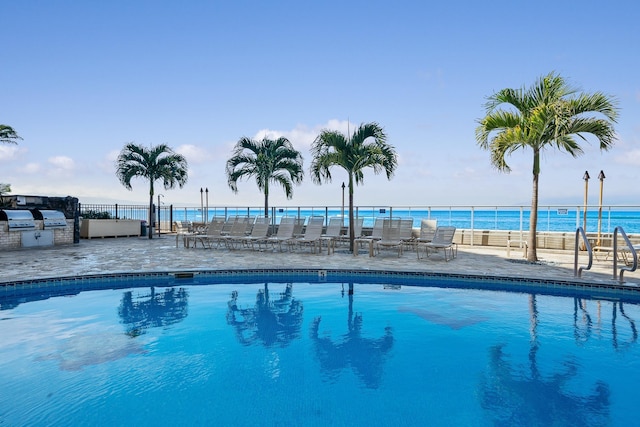 view of pool with a water view, a patio, exterior kitchen, and area for grilling