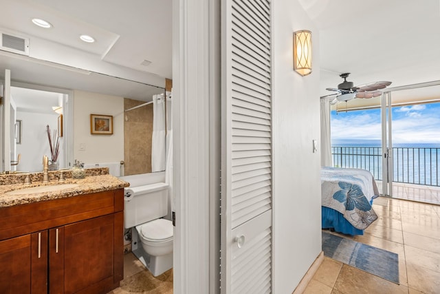 bathroom with vanity, toilet, walk in shower, a water view, and ceiling fan