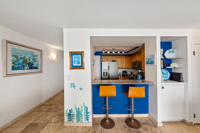 kitchen with kitchen peninsula, stainless steel fridge with ice dispenser, stove, rail lighting, and a breakfast bar area