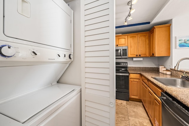 clothes washing area featuring sink, stacked washer and clothes dryer, and track lighting