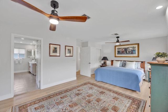 bedroom with ensuite bathroom, ceiling fan, light wood-style flooring, visible vents, and baseboards