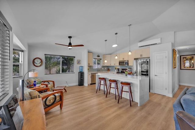 kitchen with appliances with stainless steel finishes, a breakfast bar, open floor plan, a wall mounted air conditioner, and light countertops