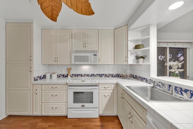 kitchen with tile countertops, light hardwood / wood-style floors, backsplash, white appliances, and sink