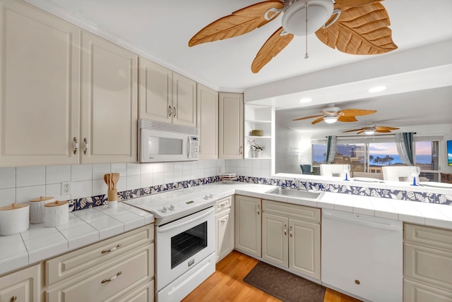 kitchen with tile countertops, sink, backsplash, and white appliances