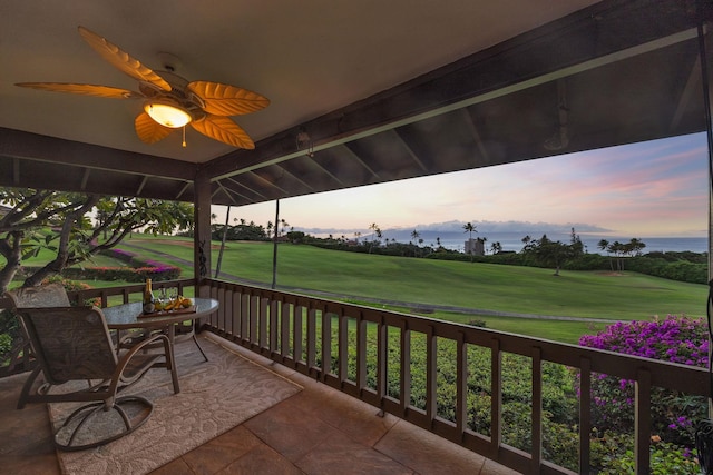 balcony at dusk featuring ceiling fan