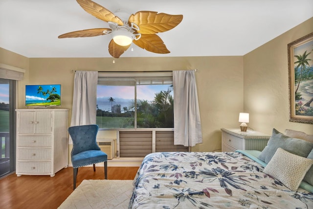 bedroom featuring ceiling fan, multiple windows, wood-type flooring, and radiator