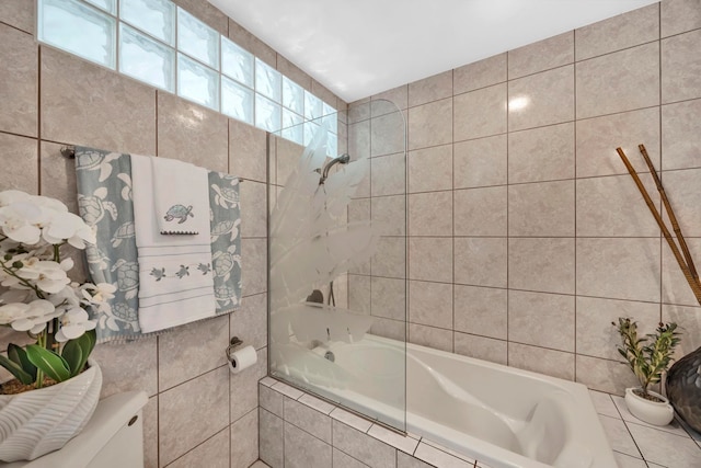 bathroom featuring toilet, tile walls, and tiled shower / bath