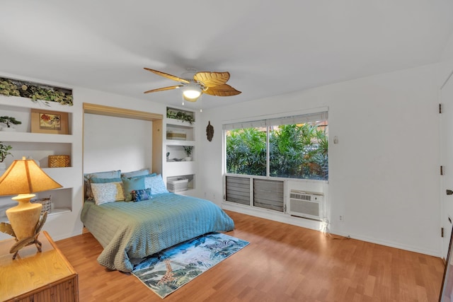 bedroom with ceiling fan, hardwood / wood-style flooring, and an AC wall unit