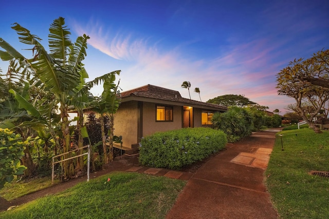 property exterior at dusk featuring a lawn