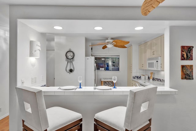 bar with ceiling fan, tile counters, backsplash, and white appliances