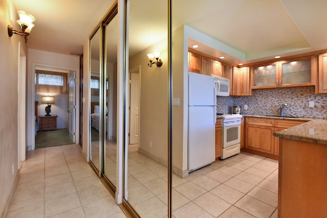 kitchen featuring sink, white appliances, light tile flooring, backsplash, and light stone countertops