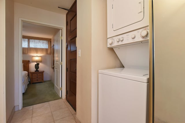 laundry area featuring light tile flooring and stacked washing maching and dryer