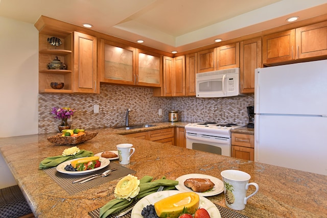 kitchen featuring sink, white appliances, tasteful backsplash, a raised ceiling, and light stone countertops