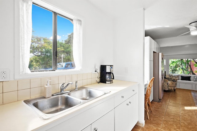 kitchen with stainless steel fridge, sink, white cabinets, and a healthy amount of sunlight