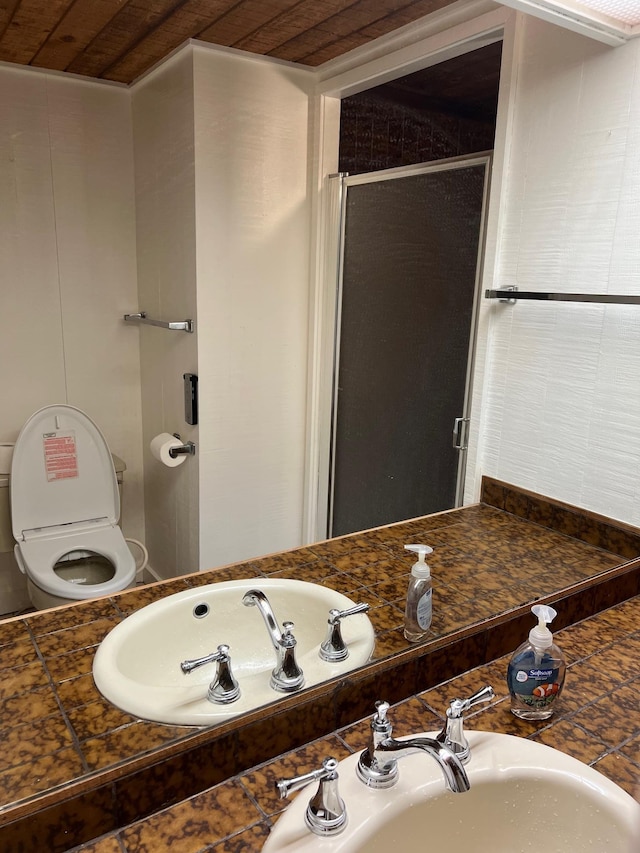 bathroom featuring toilet, a shower with door, wooden ceiling, and sink