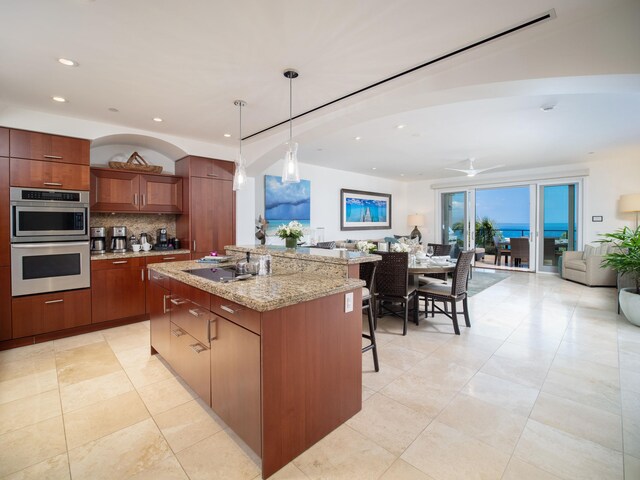 kitchen with ceiling fan, tasteful backsplash, double oven, decorative light fixtures, and a kitchen island