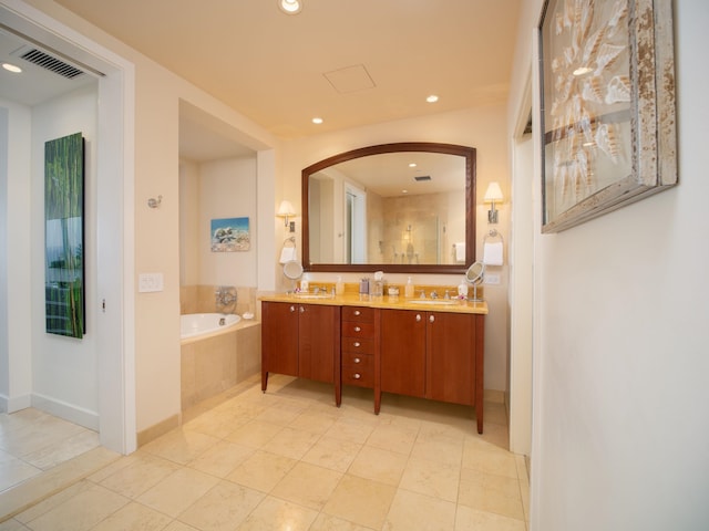 bathroom with tile patterned flooring, vanity, and tiled bath