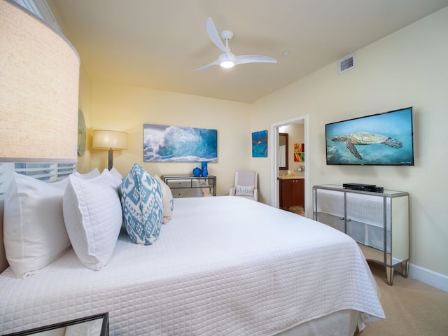 carpeted bedroom with ensuite bath and ceiling fan