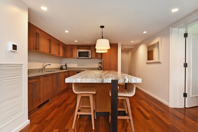 kitchen with a kitchen breakfast bar, dark hardwood / wood-style flooring, hanging light fixtures, and sink