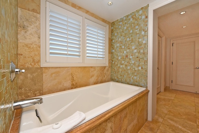 bathroom featuring tile patterned floors, tiled bath, and tile walls