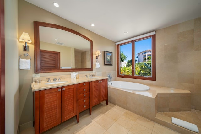 bathroom with a relaxing tiled tub, vanity, and tile patterned flooring