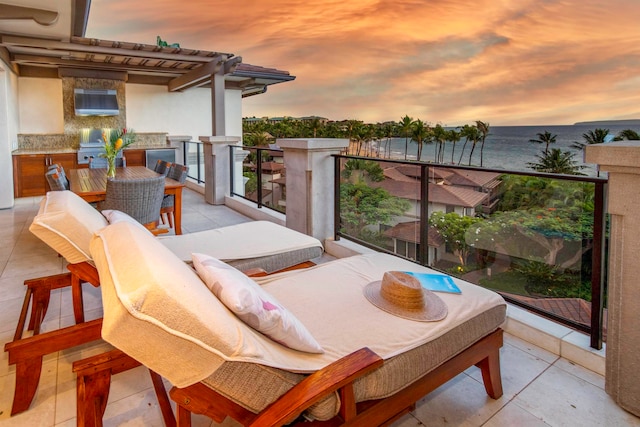 balcony at dusk featuring a water view