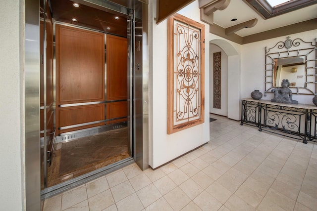 hall with light tile patterned floors and elevator