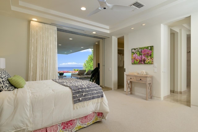 bedroom with a tray ceiling, ceiling fan, and light colored carpet