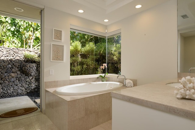 bathroom featuring tile patterned flooring, plenty of natural light, a relaxing tiled tub, and vanity