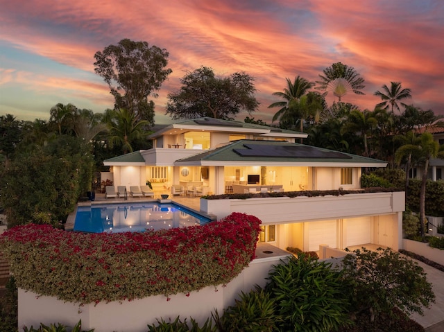 pool at dusk featuring a patio area and outdoor lounge area