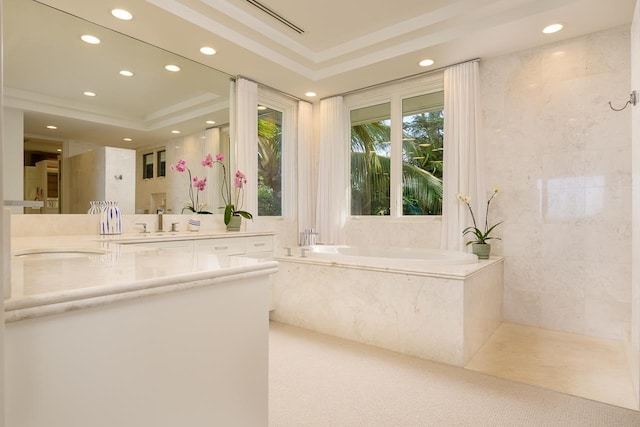 bathroom with a raised ceiling, vanity, a bath, and tile walls