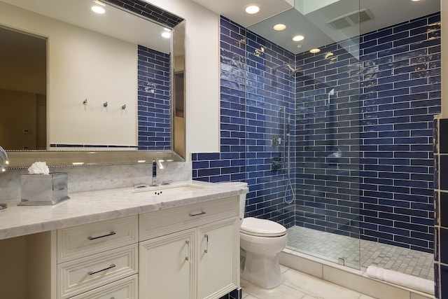 bathroom with vanity, tile patterned flooring, decorative backsplash, toilet, and a tile shower