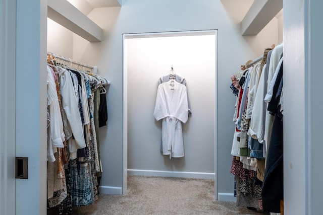 walk in closet featuring light colored carpet and lofted ceiling