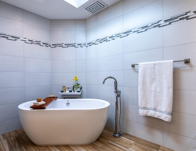 bathroom with a tub, hardwood / wood-style floors, and tile walls