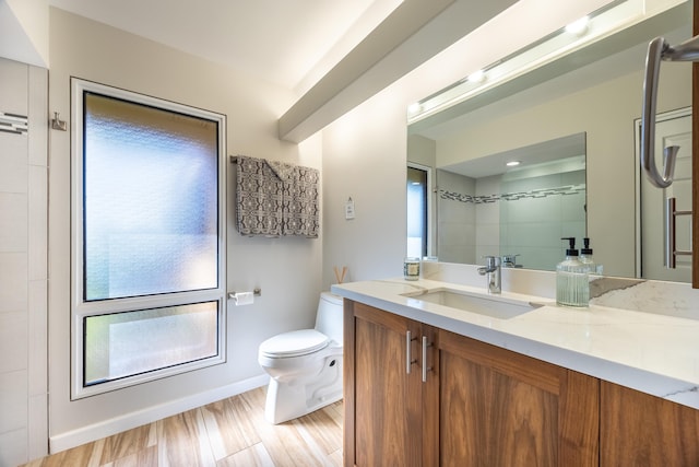 bathroom with hardwood / wood-style flooring, tiled shower, vanity, and toilet