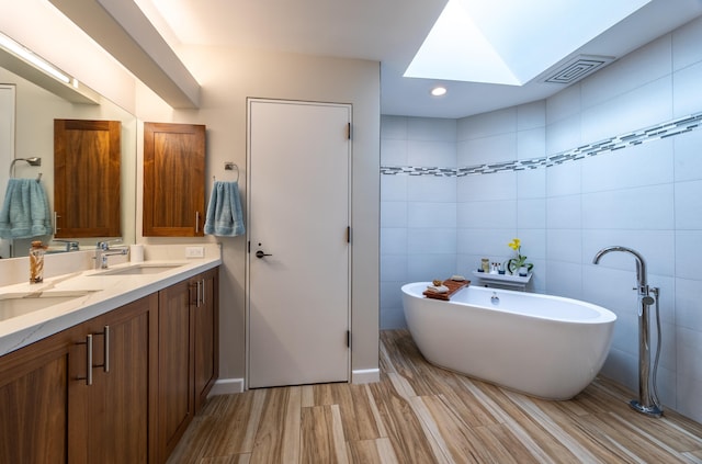 bathroom featuring a tub, tile walls, vanity, and a skylight