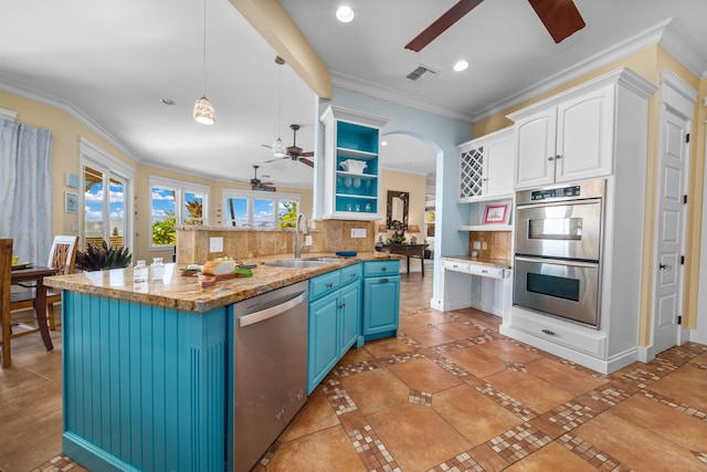 kitchen with pendant lighting, sink, blue cabinetry, tasteful backsplash, and stainless steel appliances