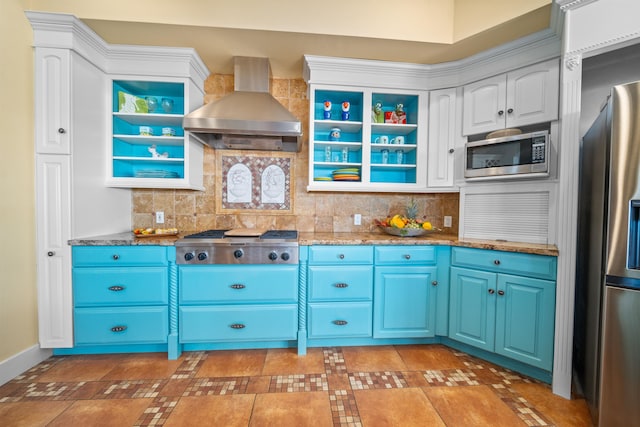 kitchen with appliances with stainless steel finishes, backsplash, wall chimney exhaust hood, blue cabinetry, and white cabinetry