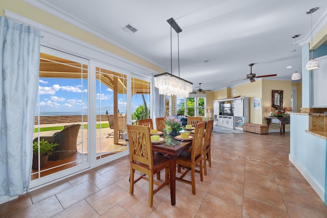 dining room featuring light tile patterned floors, ceiling fan with notable chandelier, a water view, and ornamental molding