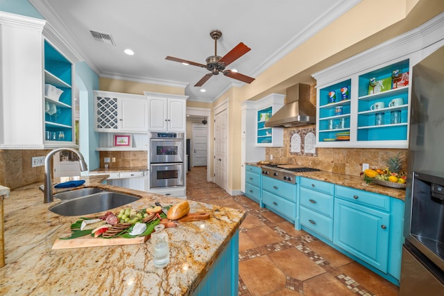 kitchen featuring blue cabinetry, sink, wall chimney range hood, white cabinets, and appliances with stainless steel finishes