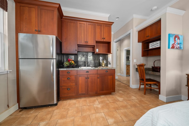 kitchen featuring stainless steel fridge, tasteful backsplash, light stone counters, crown molding, and sink