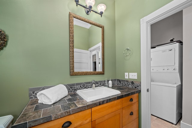 bathroom featuring tile patterned flooring, vanity, and stacked washer / dryer