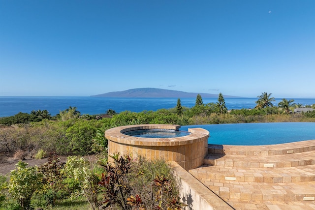 view of swimming pool with an in ground hot tub and a water and mountain view